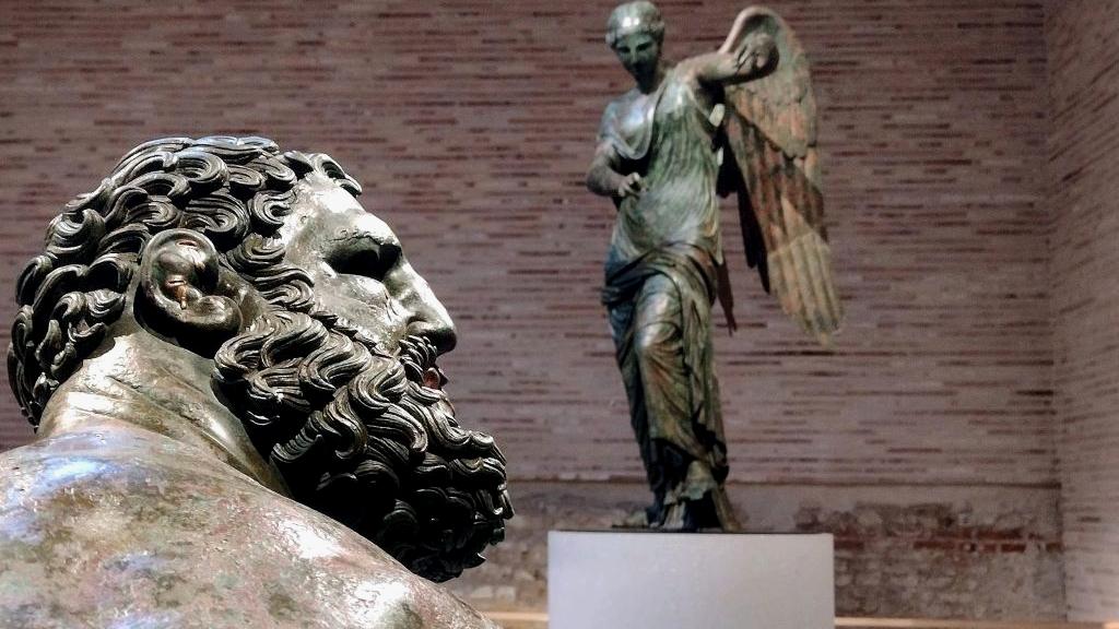 Statue romane con pugile in primo piano e figura sullo sfondo, simbolo di equilibrio tra forza e controllo nelle operazioni immobiliari
